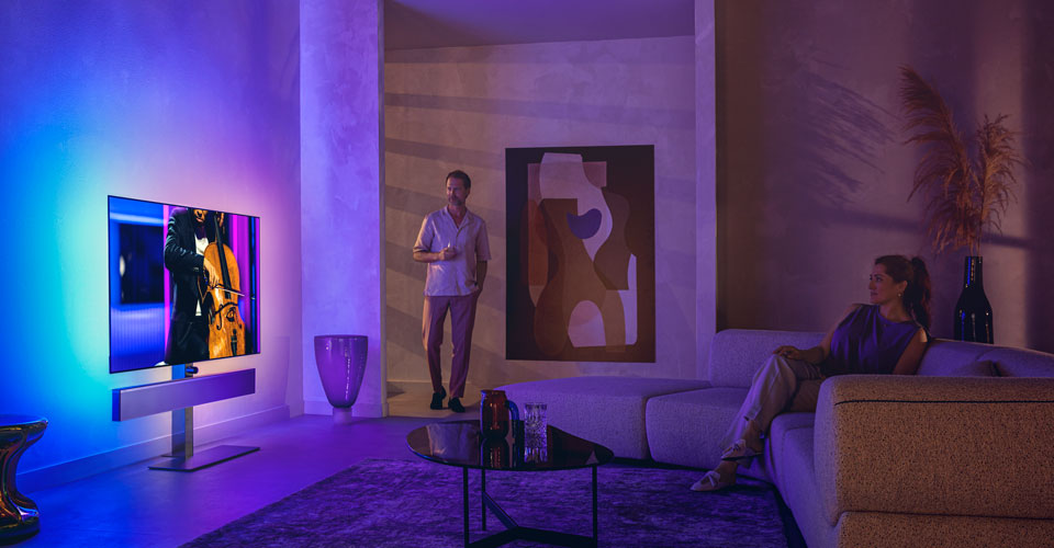 Mees ja naine stiilses elutoas vaatavad Philipsi Ambilight-telerit, millelt avaneb t&scaron;elloesinemine